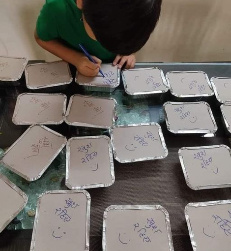 Mother cooking food for pregnant women in hospital, son writing ‘खुश रहिये’ (Be Happy) on the food boxes.